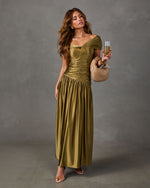 Olive green satin off-shoulder maxi dress with ruched bodice and drop waist, styled with woven clutch and champagne flute