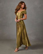 Woman in an olive green satin off-the-shoulder maxi dress with ruched bodice, gold cuff bracelet and nude heeled sandals