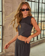 Woman in charcoal gray cropped muscle tank top and matching wide-leg sweatpants, styled with black rectangular sunglasses and gold hoop earrings