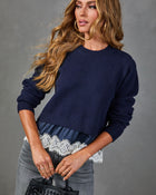 Navy blue knit cropped sweater with white lace hem and satin detail, styled with gray jeans and mini handbag