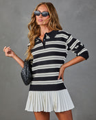 Woman wearing black and white striped polo sweater mini dress with pleated hem, cat-eye sunglasses, and woven leather bag