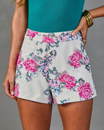 White sequin floral shorts with pink rose embellishments, paired with teal bodysuit and gold bangles