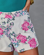 White sequin floral shorts with pink rose embellishments, paired with a teal top and gold bangles