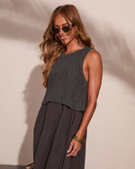 Woman wearing dark gray crochet knit crop top over flowy maxi dress, gold bangles, retro sunglasses, wavy hair