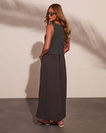 Woman wearing charcoal crochet crop top with lace-back detail and matching maxi skirt, styled with sandals and sunglasses