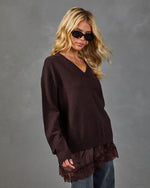 Woman wearing oversized dark burgundy v-neck knit sweater with lace hem over satin slip, paired with jeans and sunglasses