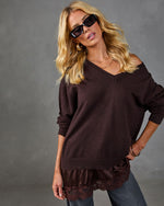 Dark brown V-neck knit sweater with satin and lace hem ruffle, worn off-shoulder by blonde model with sunglasses