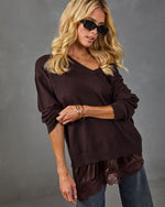 Woman wearing dark brown v-neck sweater with lace-trim satin hem, styled with jeans and black sunglasses