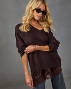 Woman wearing dark brown v-neck sweater with lace-trim satin hem, styled with jeans and black sunglasses