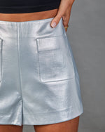 Metallic silver faux leather high-waist shorts with patch pocket, styled with black crop top