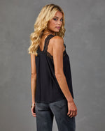 Black lace-trim camisole top on blonde woman paired with dark gray jeans, back view, studio photo