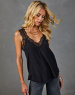 Black lace-trim satin camisole top on blonde model styled with gray jeans and layered gold necklaces