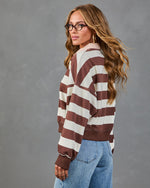 Woman wearing brown and cream striped oversized pullover sweatshirt with jeans, long wavy hair, glasses, back view