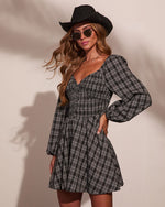 Black plaid long-sleeve mini dress with smocked bodice, styled with black cowboy hat and sunglasses on model