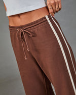 Brown drawstring sweatpants with cream side stripe, low-rise waistband, worn with white crop top