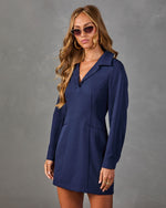 Navy blue long-sleeve mini dress with V-neck collar and front pockets, worn by blonde woman with cat-eye sunglasses
