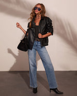 Woman wearing black leather jacket, wide-leg light wash jeans, black ankle boots, tote bag, and aviator sunglasses, fashion lookbook