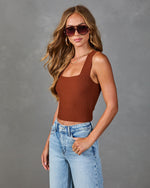 Woman wearing brown ribbed knit crop tank top and light wash high-waist wide-leg jeans with tortoise sunglasses
