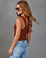 Woman wearing rust brown ribbed knit tank top bodysuit with blue jeans and tortoise sunglasses, back view