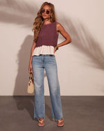 Woman wearing mauve knit crop top with cream ruffle hem, wide-leg light wash jeans, sandals, and woven bag