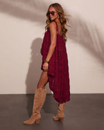 Woman in burgundy tiered midi dress with tan cowboy boots, sunglasses, and gold jewelry, boho festival style