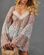 Boho floral tiered mini dress with bell sleeves, lace V-neckline trim, worn with woven bag and gold layered necklaces