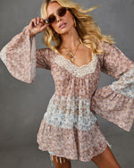 Blonde woman wearing floral boho mini dress with bell sleeves, lace neckline trim, layered tiers, and round sunglasses