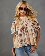 Floral print babydoll top in cream and brown botanical print with flutter sleeves, styled with blue jeans and sunglasses