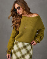 Olive green off-the-shoulder knit sweater with cable sleeves, styled with a plaid midi skirt and gold bangles
