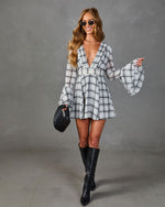 White plaid mini dress with deep V-neck, bell sleeves, worn with black knee-high boots and quilted bag