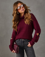 Burgundy ribbed turtleneck sweater with cutout sleeves, styled with gray jeans, aviator sunglasses and a quilted mini bag