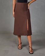 Brown midi skirt with front slit, high waist, worn with black strappy heels and gold cuff bracelet