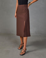 Brown midi skirt with front slit, paired with black strappy heels and gold bangles, modeled on gray background