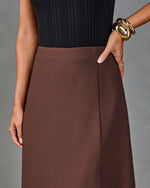 Brown A-line midi skirt with side pocket, paired with black ribbed top and gold cuff bracelet on model