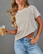 Woman in cream striped t-shirt and light wash jeans holding iced coffee, casual everyday fashion look