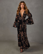 Black velvet floral maxi dress with plunging V-neckline, bell sleeves and front knot, styled with black clutch and heels