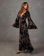 Black velvet maxi dress with brown floral print, plunging V-neckline, knotted front and wide bell sleeves, styled with heels
