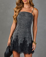 Gray acid wash denim mini dress with black lace hem trim and spaghetti straps, styled with gold jewelry and woven clutch