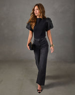 Black puff-sleeve top with high-waisted black wide-leg jeans, gold cuff bracelets, black clutch and pointed-toe heels