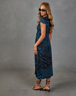 Woman modeling teal blue leopard print midi dress with cap sleeves, black lace-up kitten heel sandals, and sunglasses