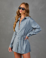Woman wearing slate blue long-sleeve button-down mini shirt dress with drawstring waist and oversized fit, styled with sunglasses