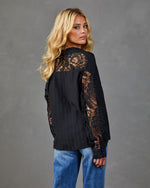 Black lace-sleeve button-up blouse with sheer floral lace back yoke, worn with blue jeans, back view