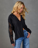 Black lace-sleeve button-down blouse on blonde woman paired with light wash jeans, floral crochet detail sleeves