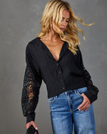 Black lace-sleeve button-down blouse on blonde model paired with high-waist blue jeans, elegant boho-chic style