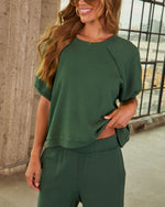 Woman wearing forest green short-sleeve cropped sweatshirt and matching wide-leg pants set, smiling outdoors