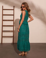 Woman modeling emerald green lace maxi dress with peplum waist, tan ankle boots, sunglasses, boho style, back view