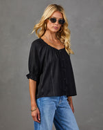 Black puff sleeve blouse with button front and elastic neckline, styled with blue jeans and gold accessories