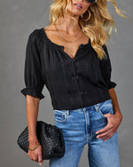 Black plaid puff sleeve crop blouse with button front, paired with high-waist blue jeans and woven leather clutch