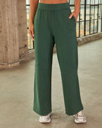 Women's forest green wide-leg high-waist athleisure pants with side pockets, worn with silver sneakers