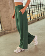 Women's high-waist wide-leg green athletic pants with side pocket, paired with white sneakers, athleisure style